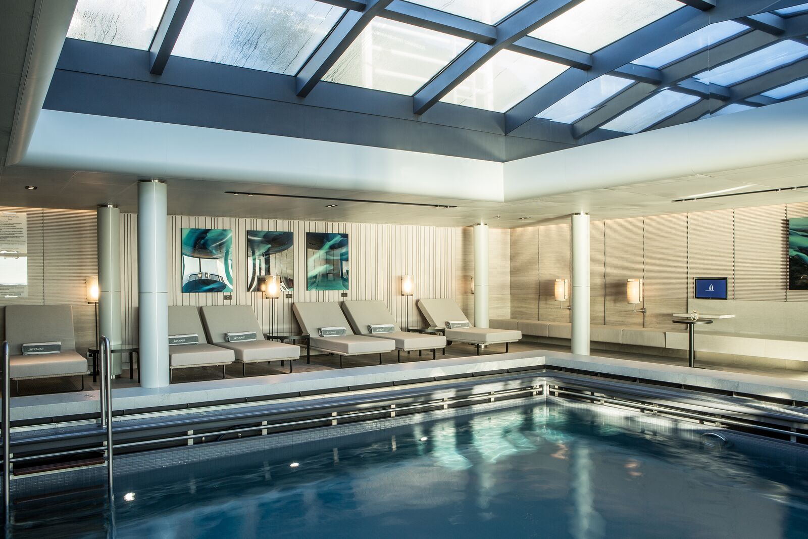 The indoor pool and loungers beneath a glass roof aboard Le Commandant Charcot