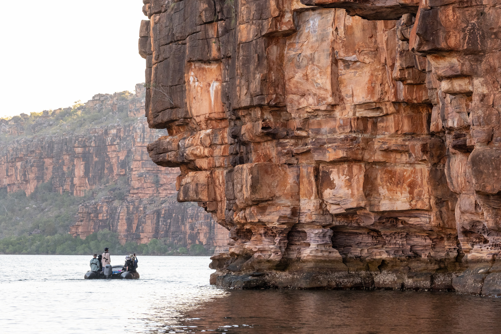 Pearl Expeditions guests exploring beneath immense Kimberley sandstone cliffs