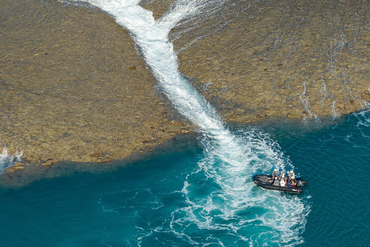 An expedition craft beside a reef revealed by the falling Kimberley tide